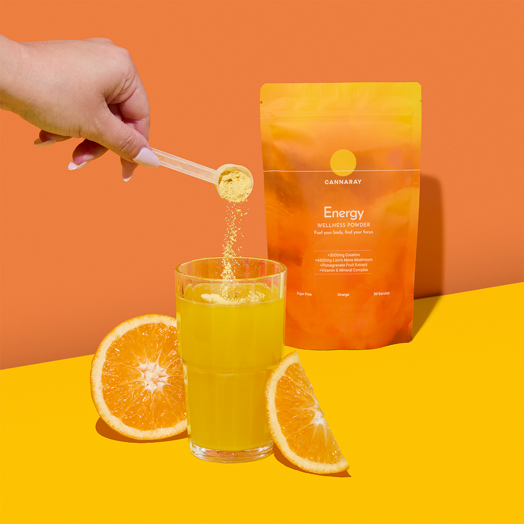 Hand pouring Cannaray's Energy Wellness Powder into a glass of water.
